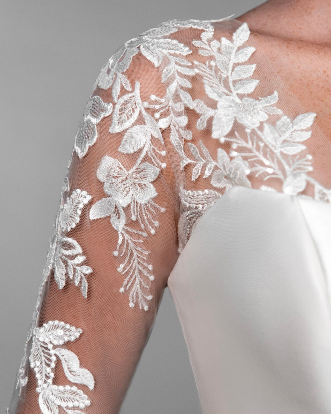 White floral lace applique on sheer long sleeves of a Stella York bridal gown.