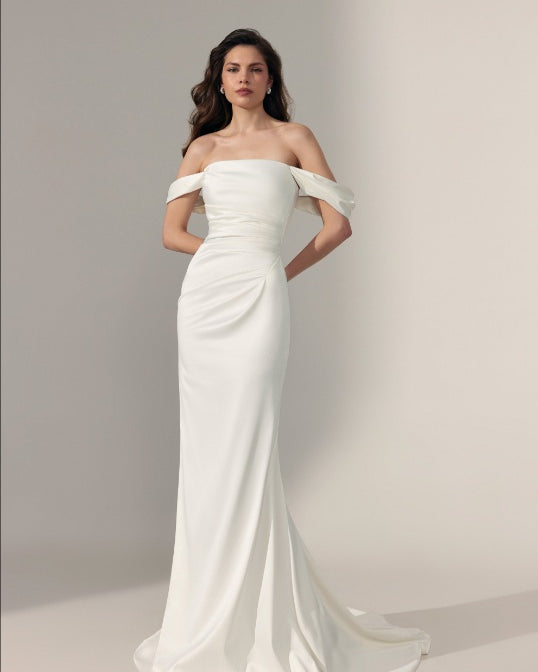 An elegant off-the-shoulder floor-length wedding gown in ivory satin fabric with off shoulder straps.