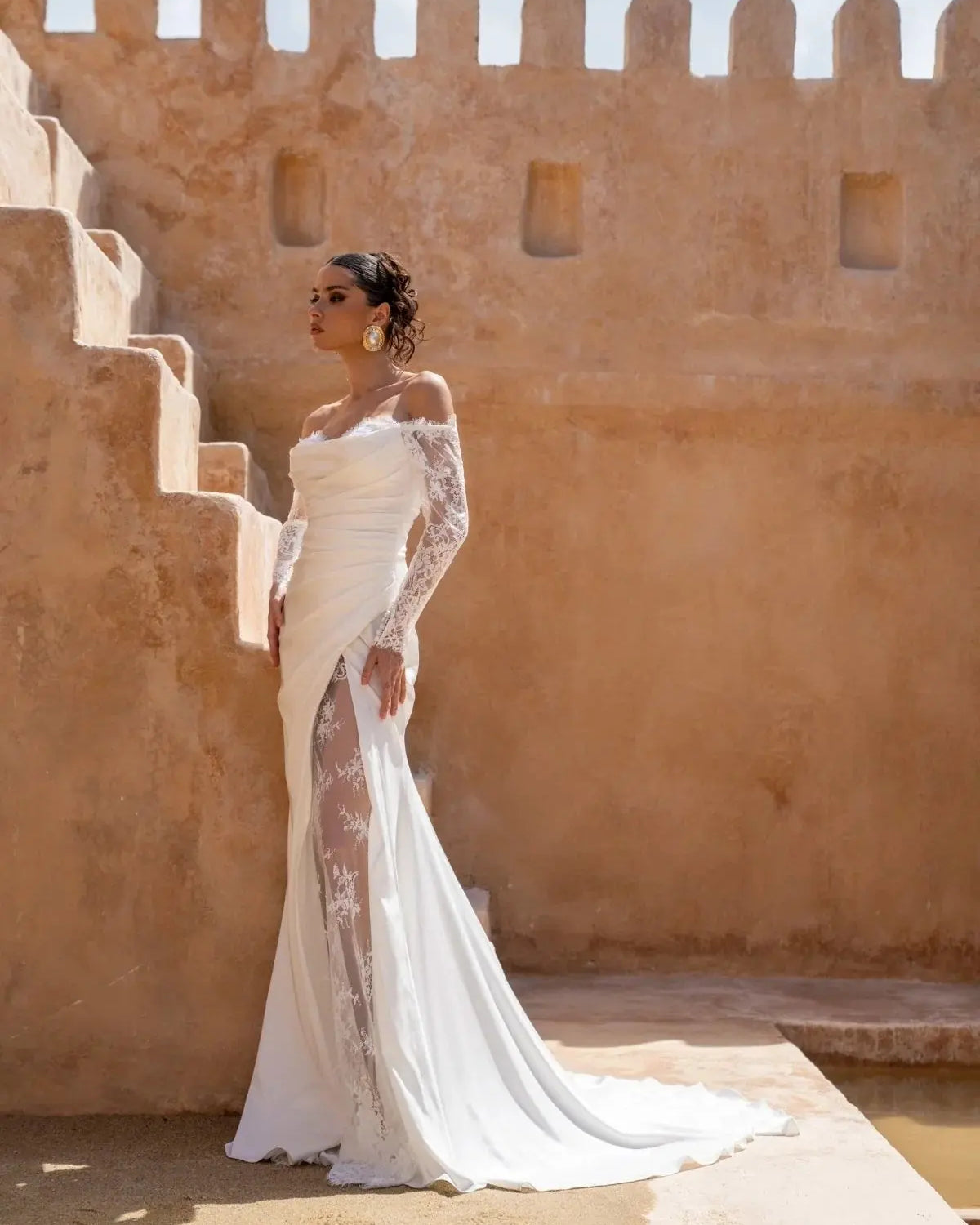 Bride wearing Lucia wedding gown by Jessica Couture, featuring draped Italian satin, long lace sleeves, sweetheart neckline, and a lace slit detail.