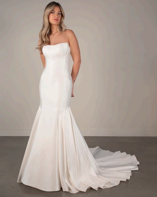 Bride wearing a strapless white ivory wedding dress with a long train, strapless neckline and mermaid fit and flare train.
