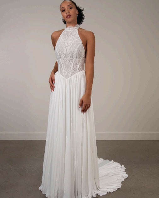 Woman wearing a white ivory lace halter neck wedding dress with chiffon skirt.