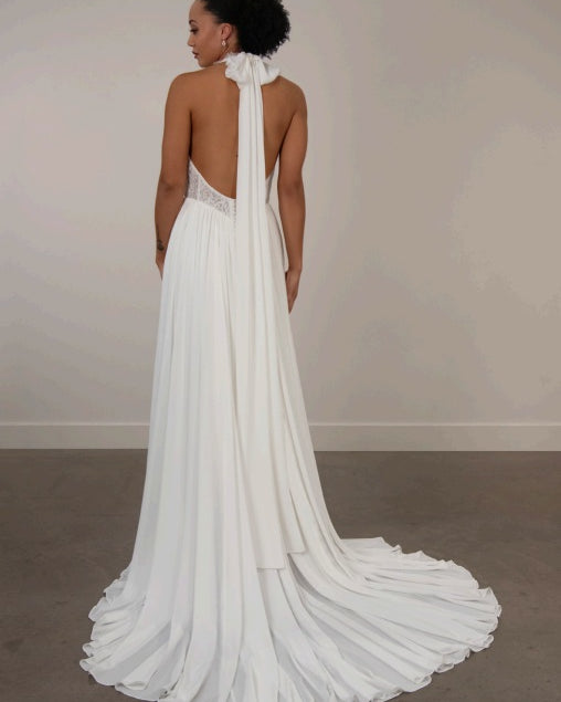 Bride wearing a white ivory chiffon wedding dress with a long train, lace bodice and low back.