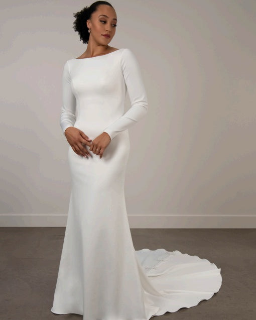 Bride wearing a white ivory boat neckline long-sleeve wedding dress with a train.