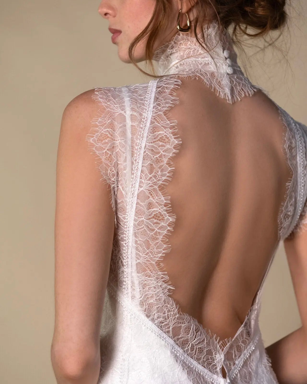 Lace and Charmeuse Sheath Wedding Dress with High Neckline and Keyhole Back. Delicate and effortless, the veda gown brings vintage romance to life with a relaxed, modern spirit. A layered two-piece look pairs an airy sandwashed charmeuse slip with a sheer lace overslip, creating soft texture and fluid movement in every step. The high neckline and slender straps lead to a striking keyhole back, while vintage-inspired lace trims and finishes give the gown unique charm.