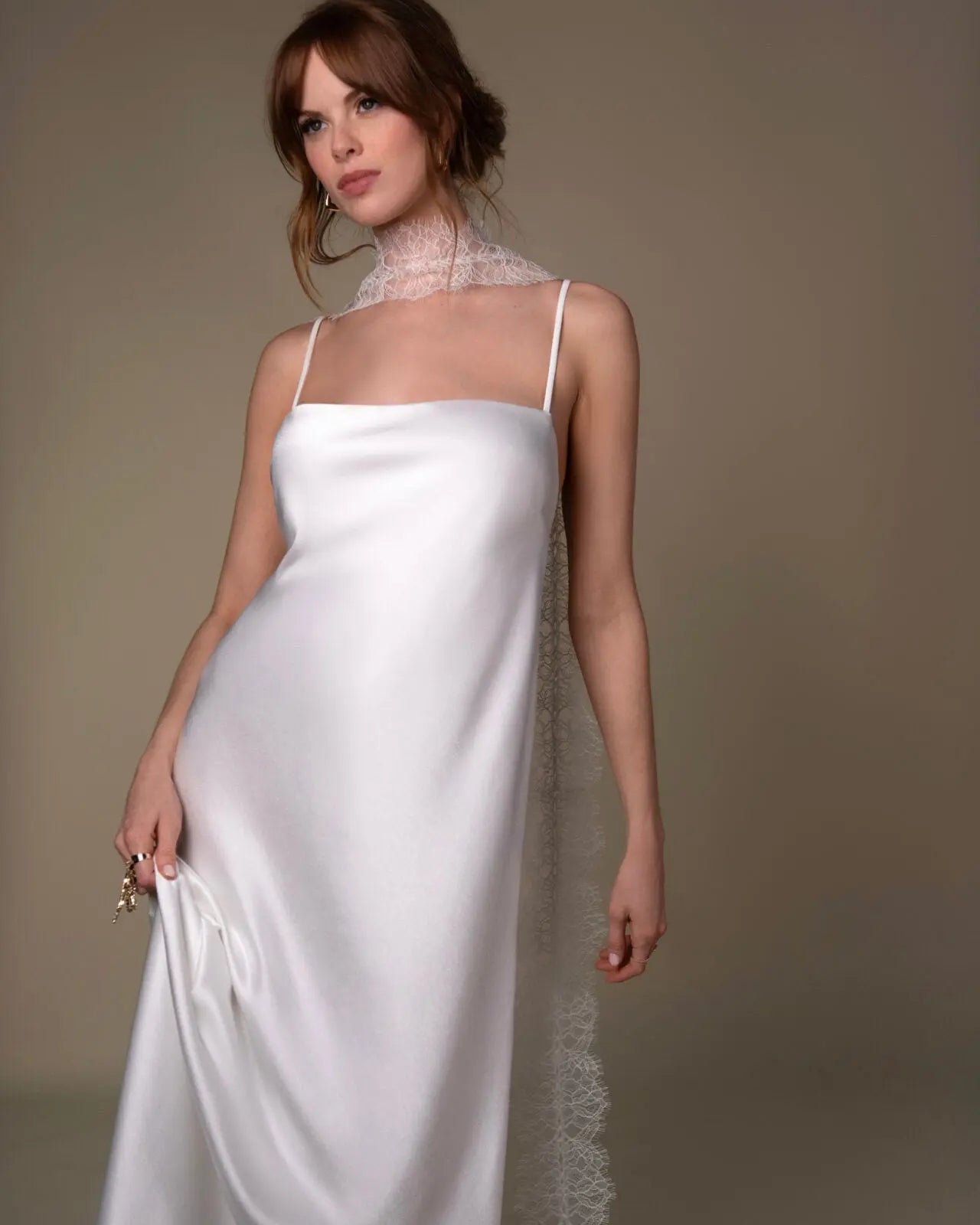 Lace and Charmeuse Sheath Wedding Dress with High Neckline and Keyhole Back. Delicate and effortless, the veda gown brings vintage romance to life with a relaxed, modern spirit. A layered two-piece look pairs an airy sandwashed charmeuse slip with a sheer lace overslip, creating soft texture and fluid movement in every step. The high neckline and slender straps lead to a striking keyhole back, while vintage-inspired lace trims and finishes give the gown unique charm.