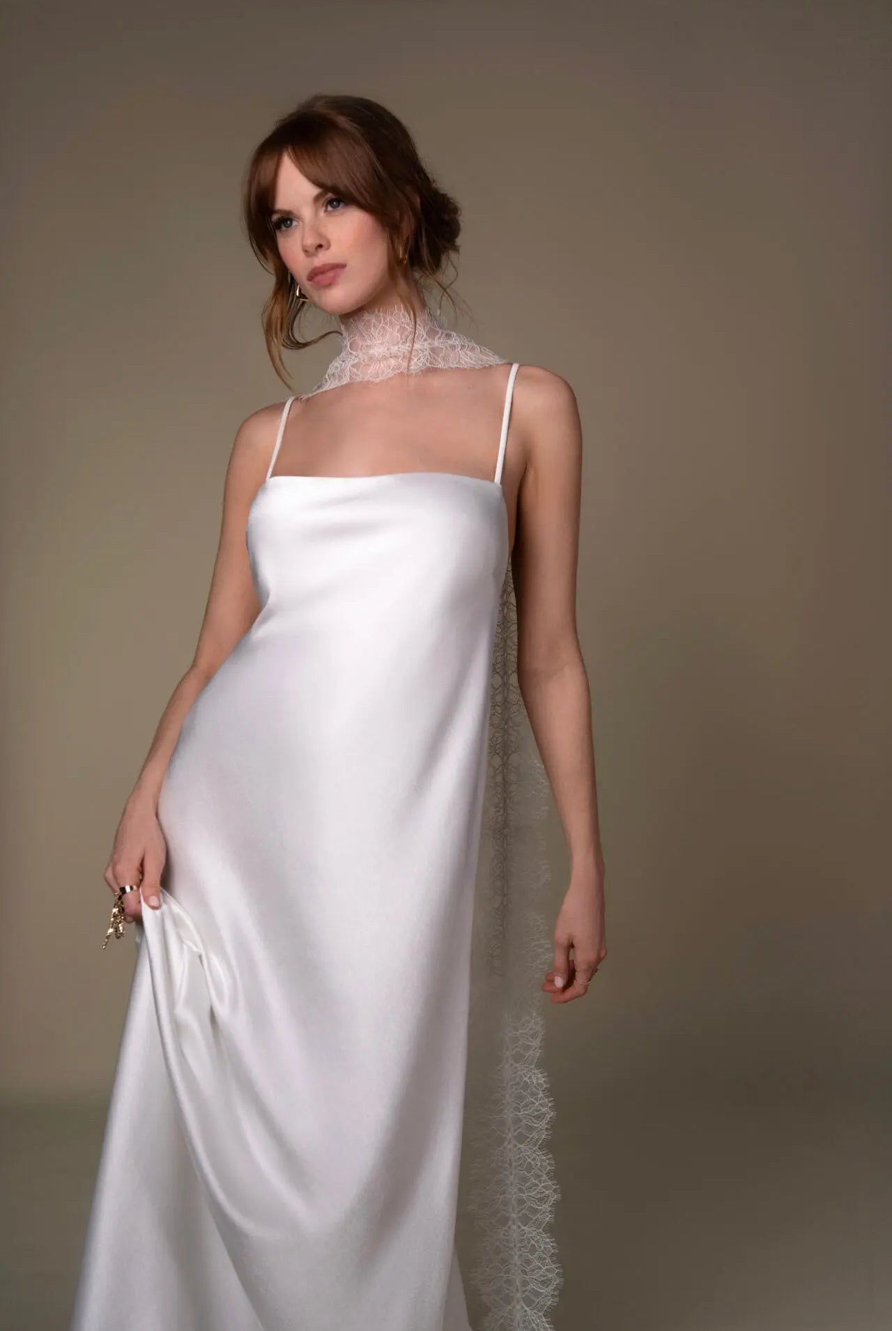 Lace and Charmeuse Sheath Wedding Dress with High Neckline and Keyhole Back. Delicate and effortless, the veda gown brings vintage romance to life with a relaxed, modern spirit. A layered two-piece look pairs an airy sandwashed charmeuse slip with a sheer lace overslip, creating soft texture and fluid movement in every step. The high neckline and slender straps lead to a striking keyhole back, while vintage-inspired lace trims and finishes give the gown unique charm.