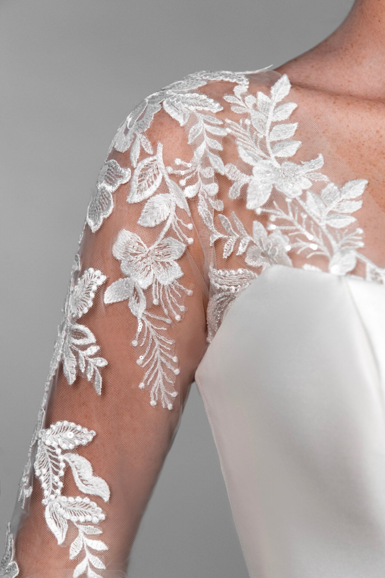 White floral lace applique on sheer long sleeves of a Stella York bridal gown.