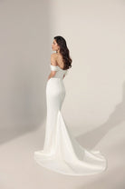 Off-the-shoulder ivory mermaid-style wedding gown with a long train.