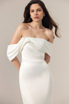 Off-the-shoulder ivory satin wedding dress with a draped, gathered bodice and a fitted skirt.