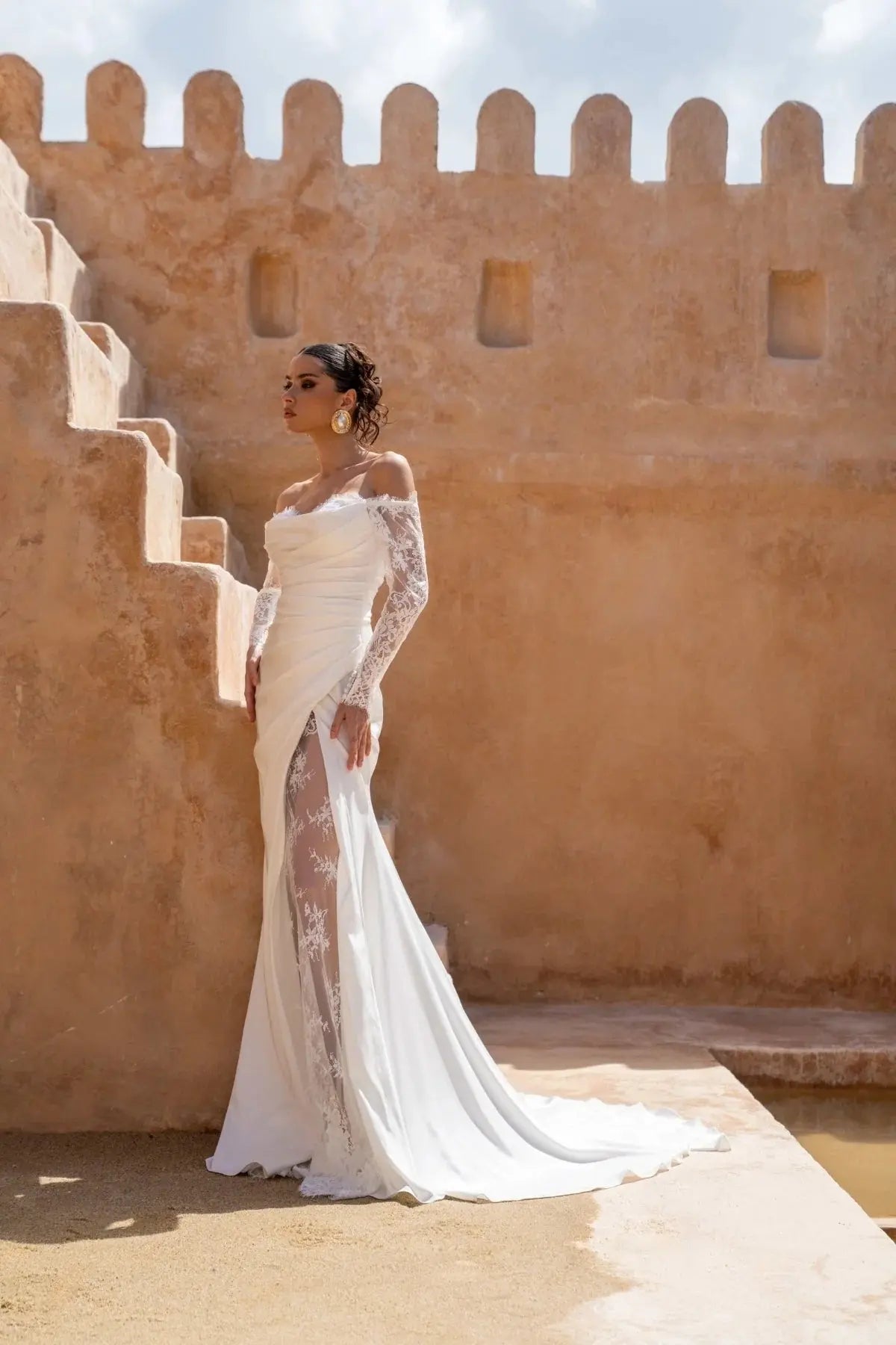 Bride wearing Lucia wedding gown by Jessica Couture, featuring draped Italian satin, long lace sleeves, sweetheart neckline, and a lace slit detail.