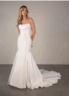 Bride wearing a strapless white ivory wedding dress with a long train, strapless neckline and mermaid fit and flare train.