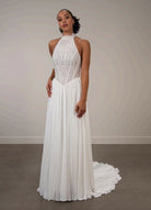 Woman wearing a white ivory lace halter neck wedding dress with chiffon skirt.