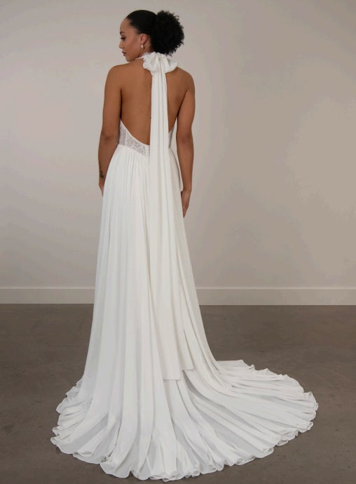 Bride wearing a white ivory chiffon wedding dress with a long train, lace bodice and low back.