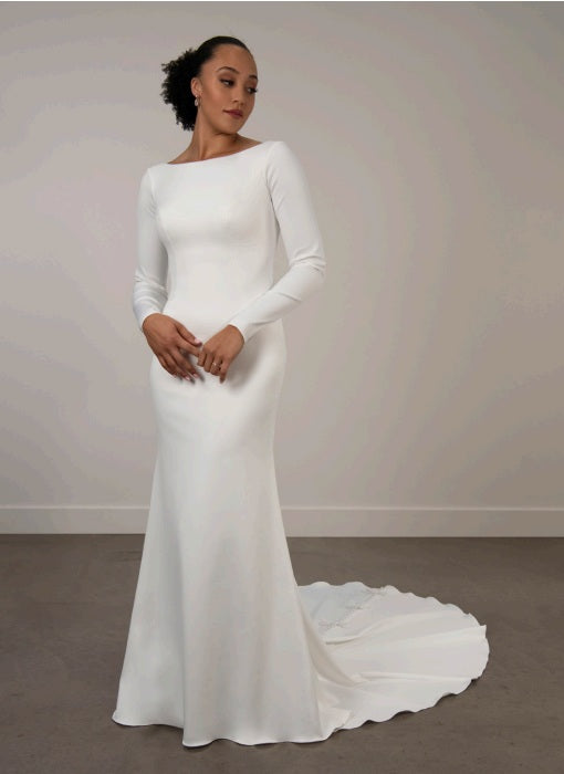 Bride wearing a white ivory boat neckline long-sleeve wedding dress with a train.